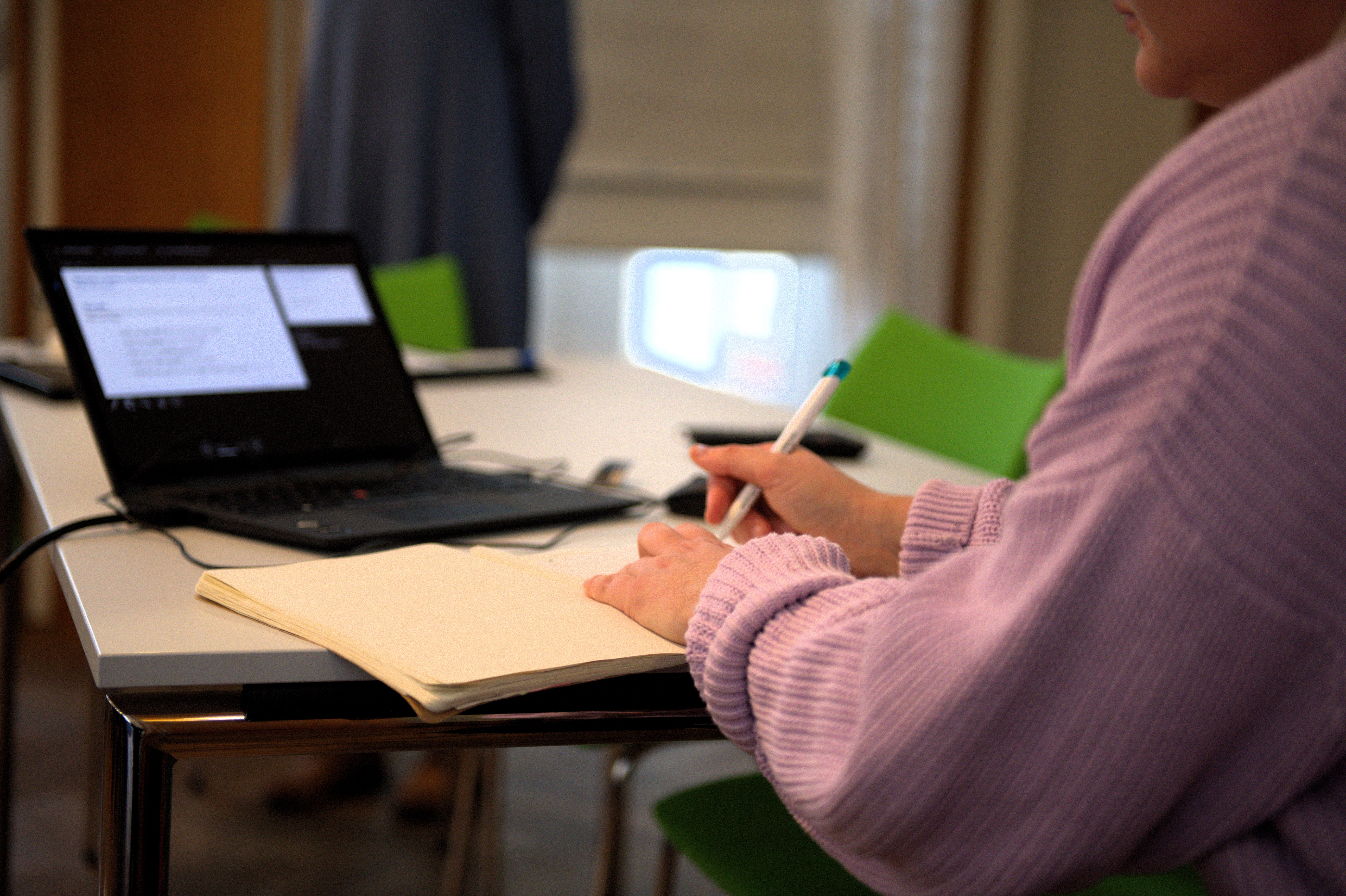 Person sitzt am Tisch, der Laptop ist sichtbar